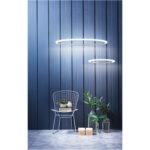 lampadario led a sospensione a soffitto rotondo due anelli sottili in alluminio colore bianco sopra a sedia piante e libri
